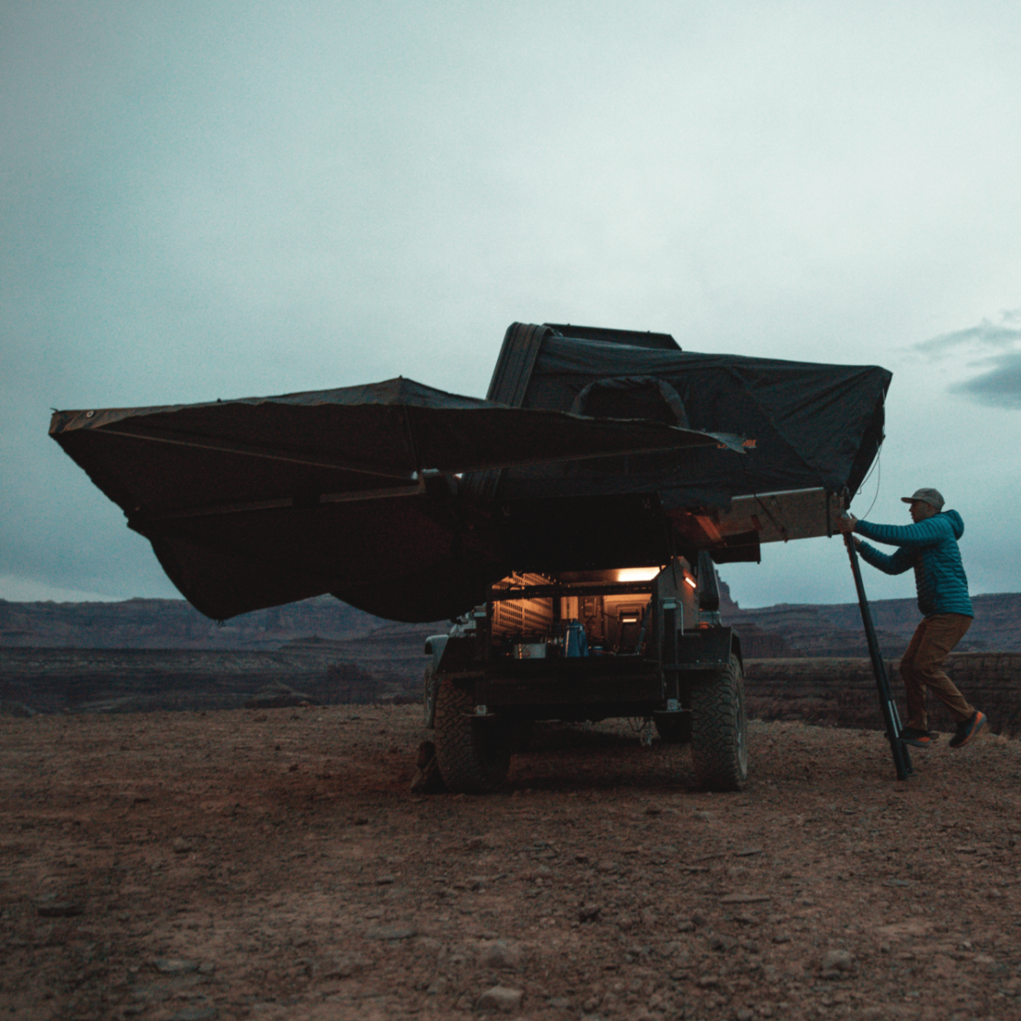ADDAX trailer with awning extended at a desert canyon campsite at dusk