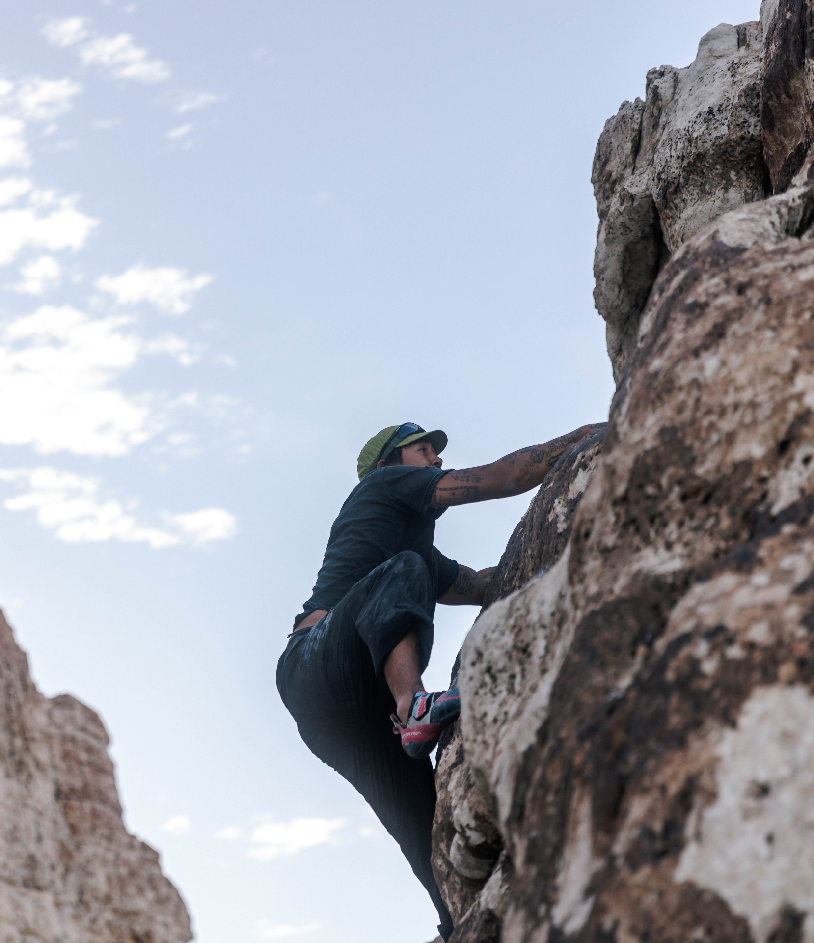 Climber scaling a desert rock face at sunset