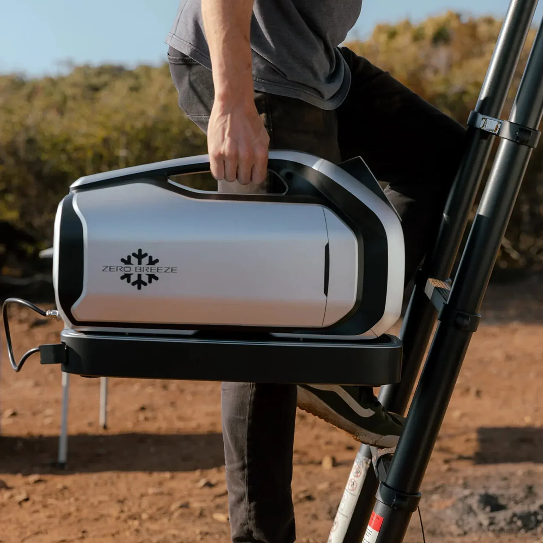 Zero Breeze portable AC unit being carried at a desert campsite